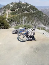 Bicycle and helmet resting on a mountain rock ledge with distant green hills.